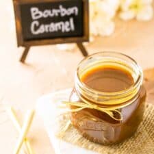 A jar of bourbon caramel sauce from up top on burlap and a marble tray.