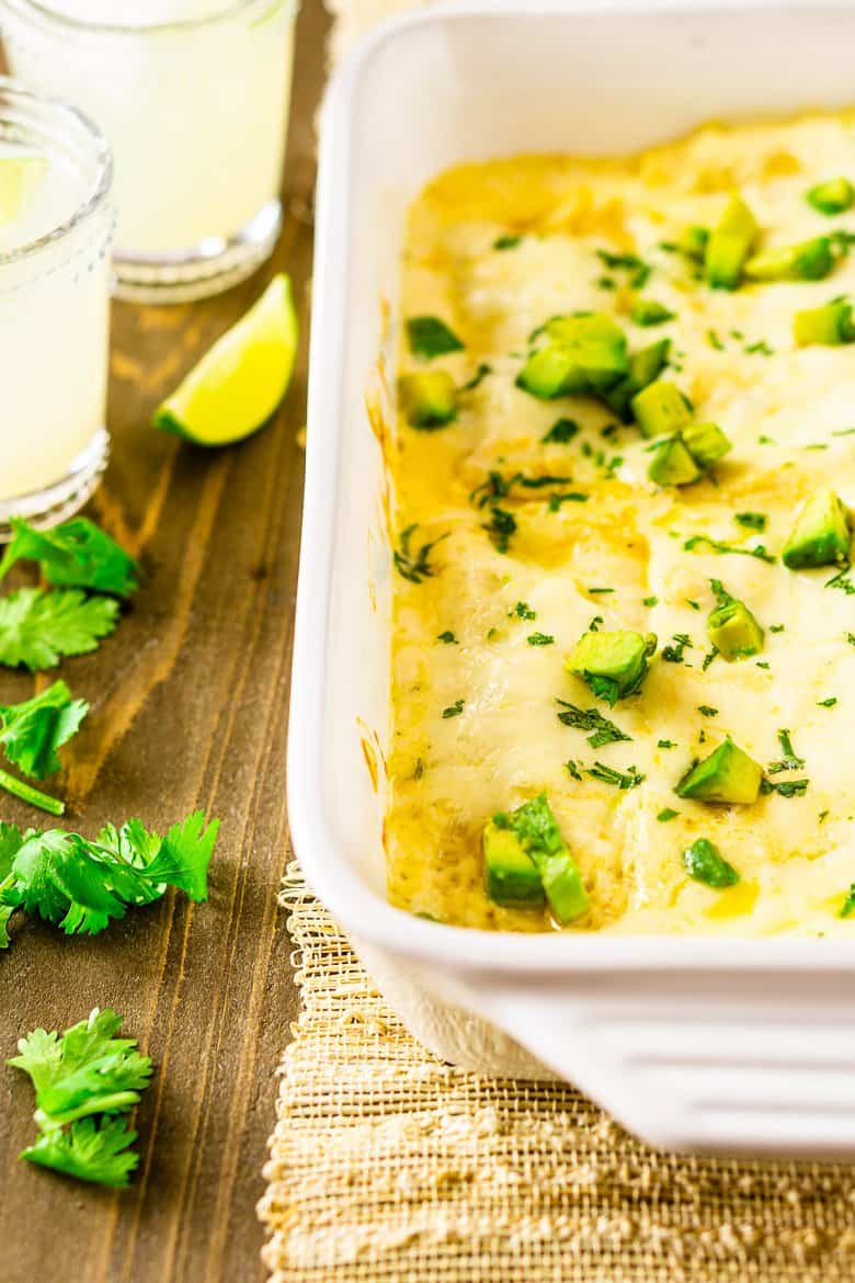 A pan of jerk chicken enchiladas with habanero-sour cream sauce with cilantro and margaritas on the side.