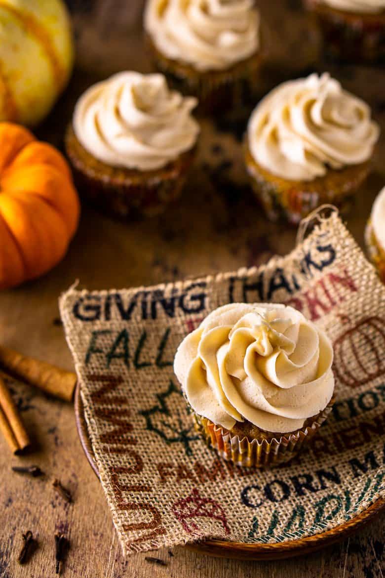 An aerial view of the brown butter-pumpkin cupcakes with two pumpkins in the background.