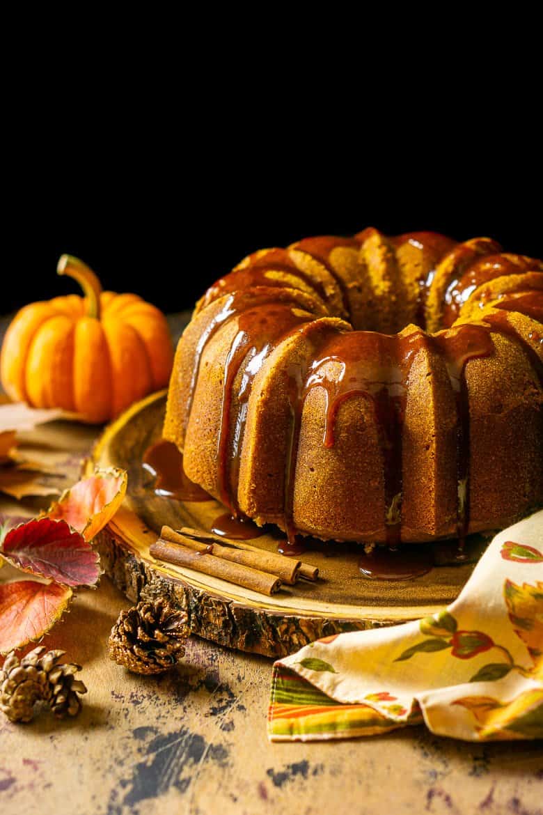 Looking slightly down on the buttermilk-pumpkin pound cake with fall foliage around it.