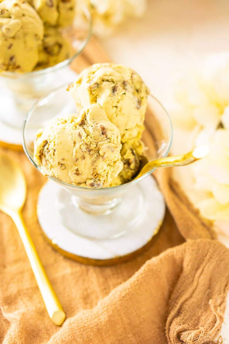 Looking into a scoop of butterscotch ice cream with a gold spoon sticking out and one gold spoon to the side.