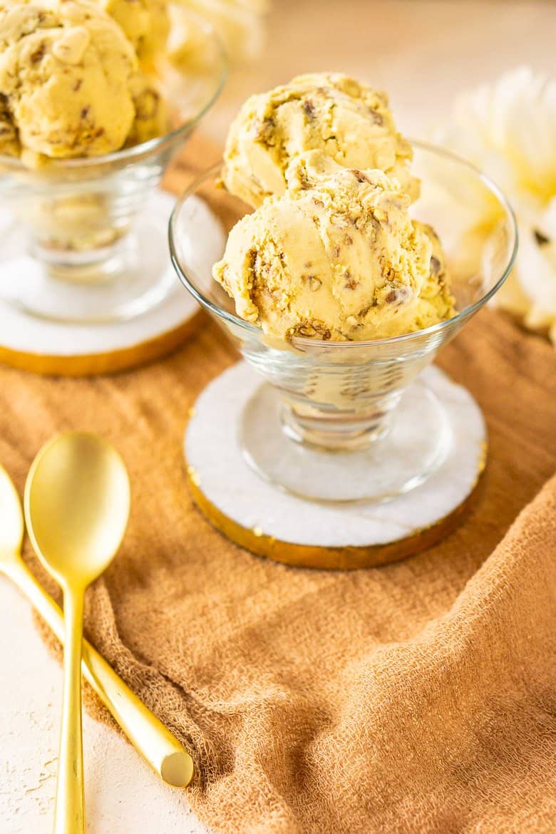 A few scoops of butterscotch ice cream with two gold spoons next to it.