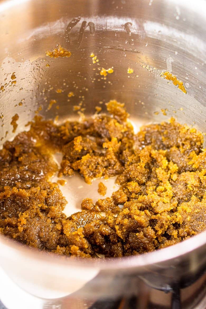 The dark brown sugar in a saucepan looking initially clumpy.