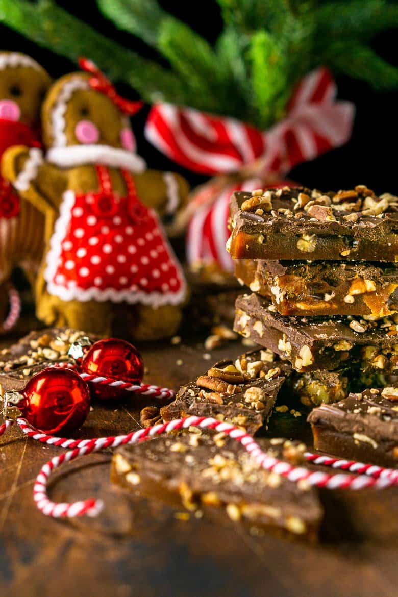 A close-up of the gingerbread toffee in a stack on the side with the gingerbread people in the background..