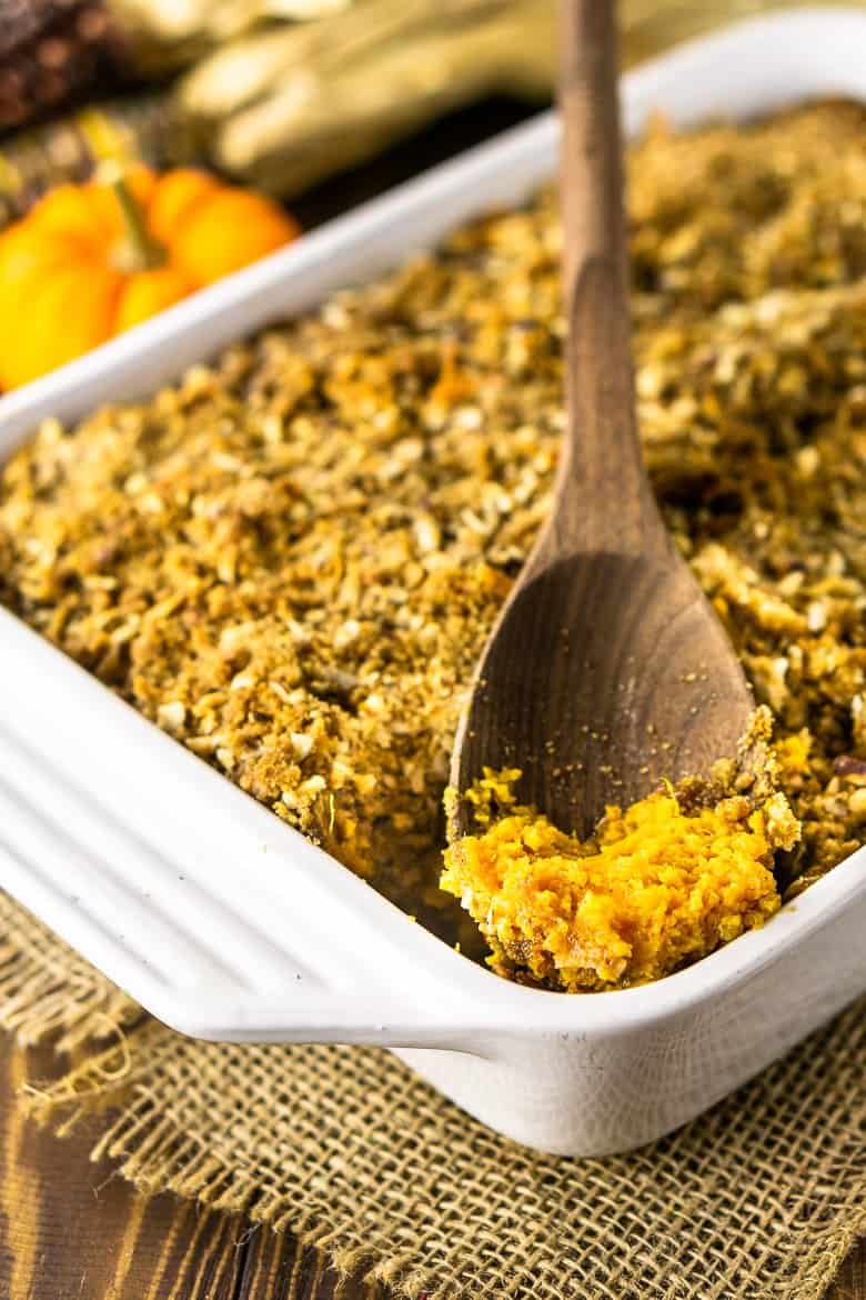 A wooden spoon in the sweet potato souffle baking dish to show off the fluffy texture.