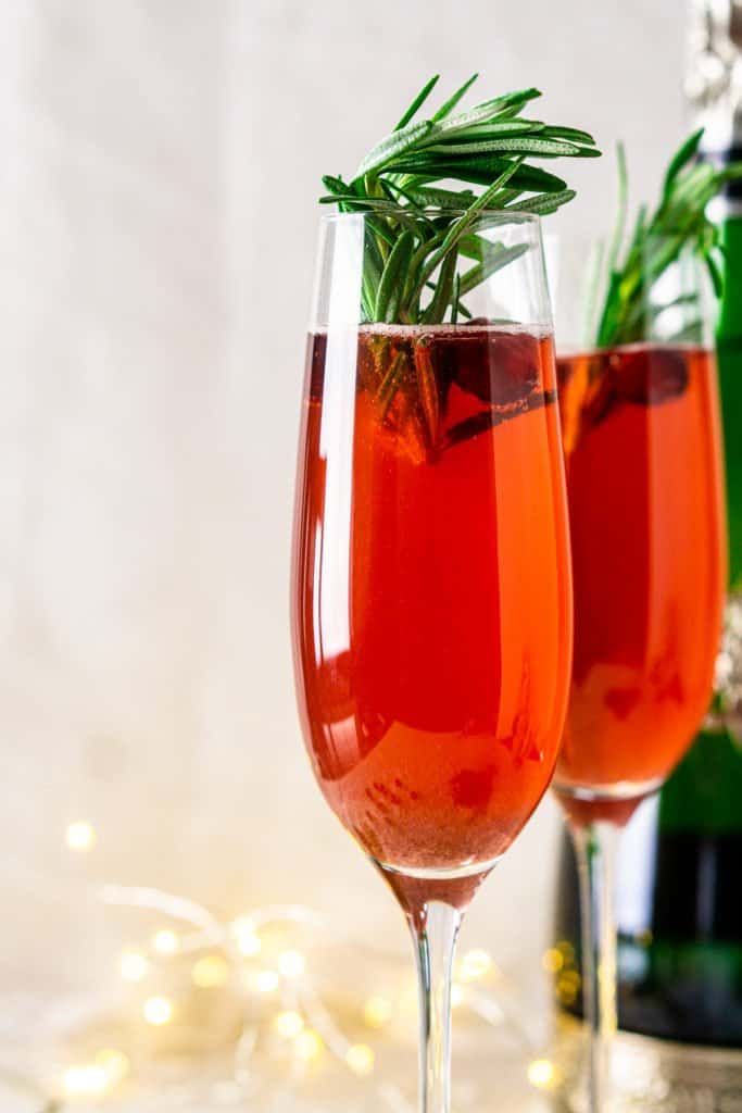 A close-up view of a cranberry-spice Christmas mimosa with lights in the background.