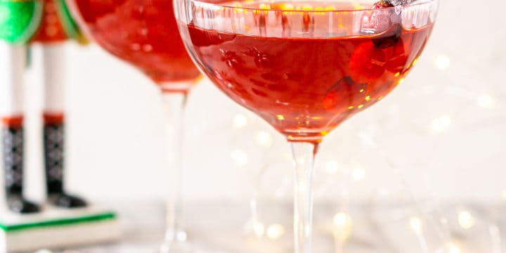 Two Sugar Plum Fairy Martinis on a marble board with a nutcracker and lights behind them.