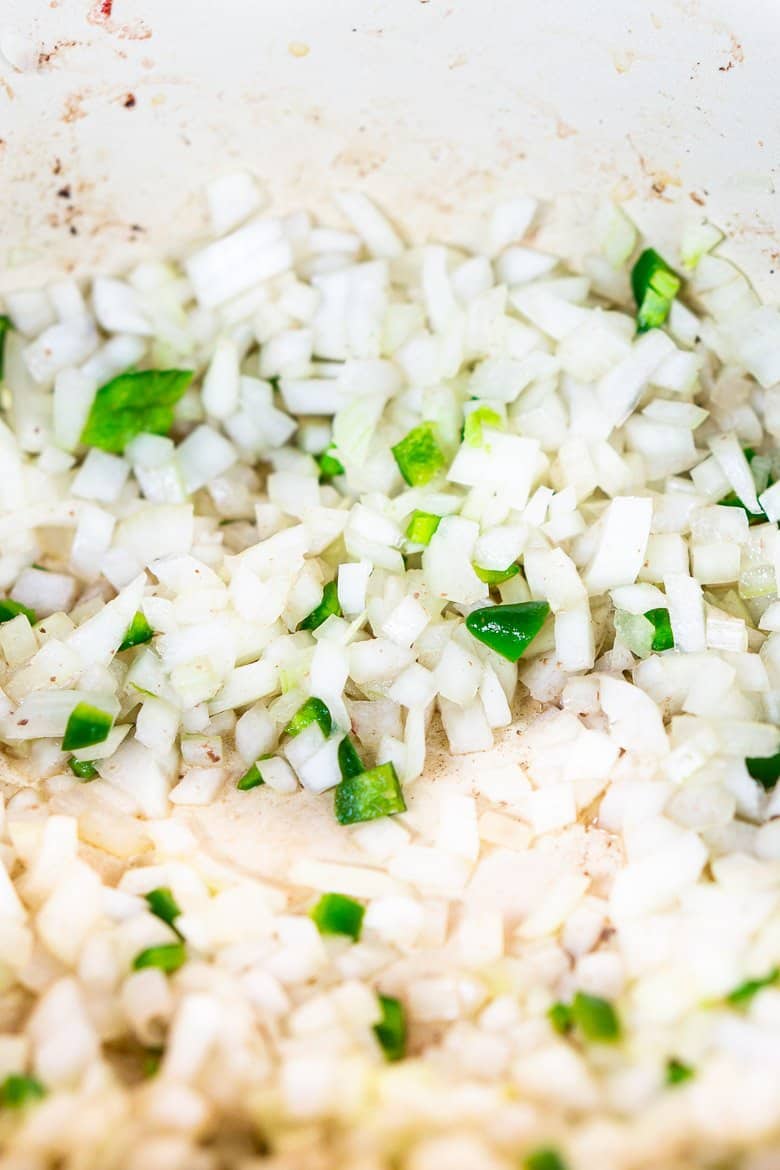 Cooking the chopped onions and jalapeno in a large Dutch oven.