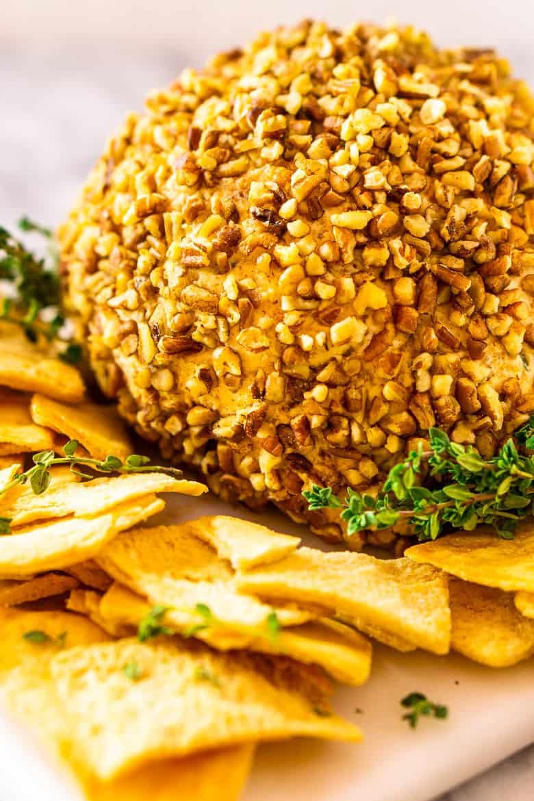 The bourbon bacon cheese ball on a white plate with pita chips surrounding it.