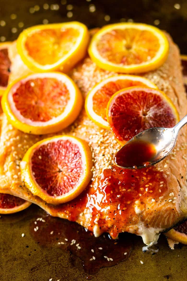 Spooning the blood orange glaze onto the slab of salmon.