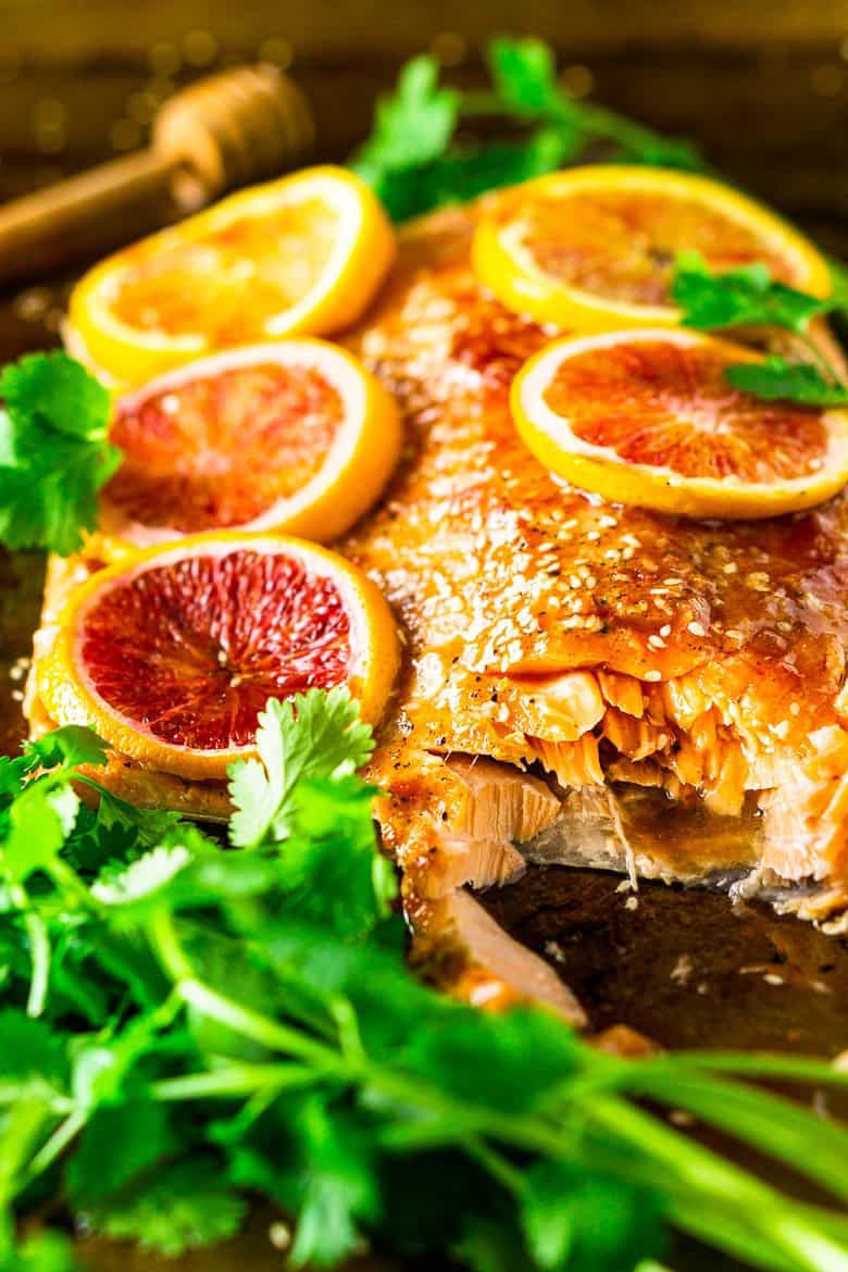 Cutting into the slab of salmon with blood orange slices on top.