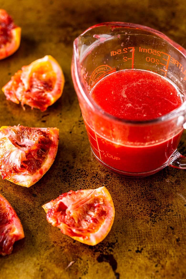 A measuring cup filled with freshly squeezed blood orange juice.