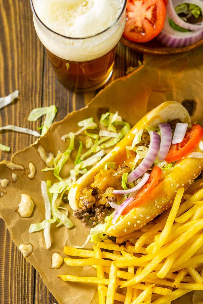 An aerial view of the cheeseburger sub with a plate of toppings and shredded lettuce scattered around it.