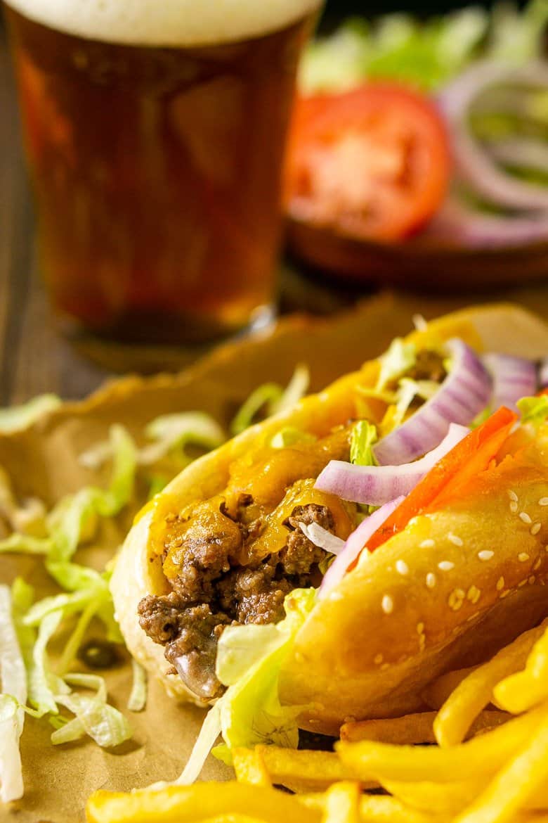 A close-up shot of the cheeseburger sub with a beer in the background.