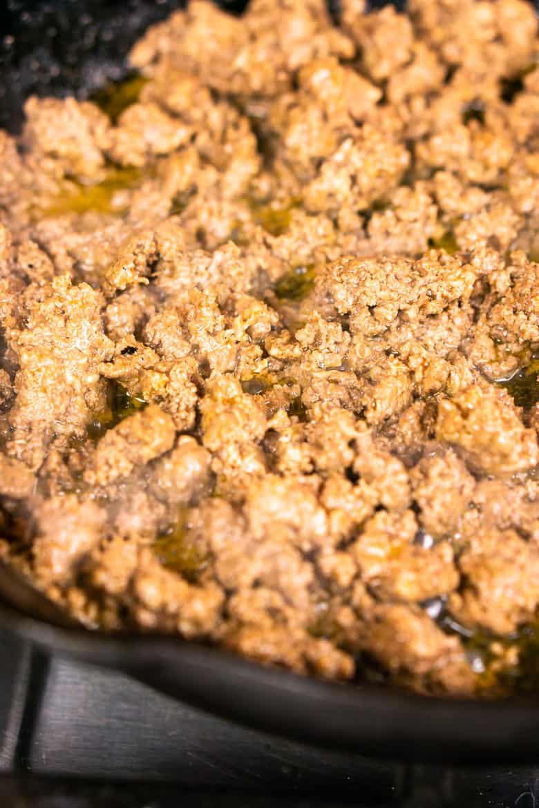 Browning the ground beef in a cast-iron skillet.