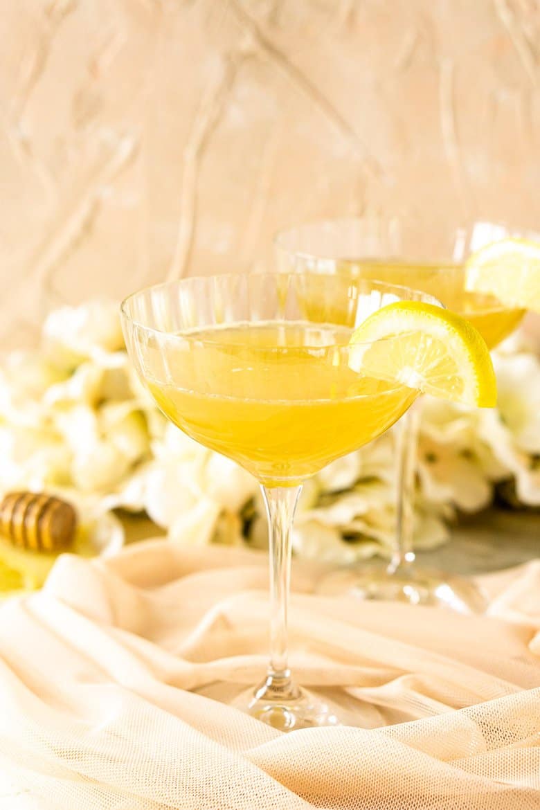 A close-up view of one gin bee's knees with flowers and a plate of honey.