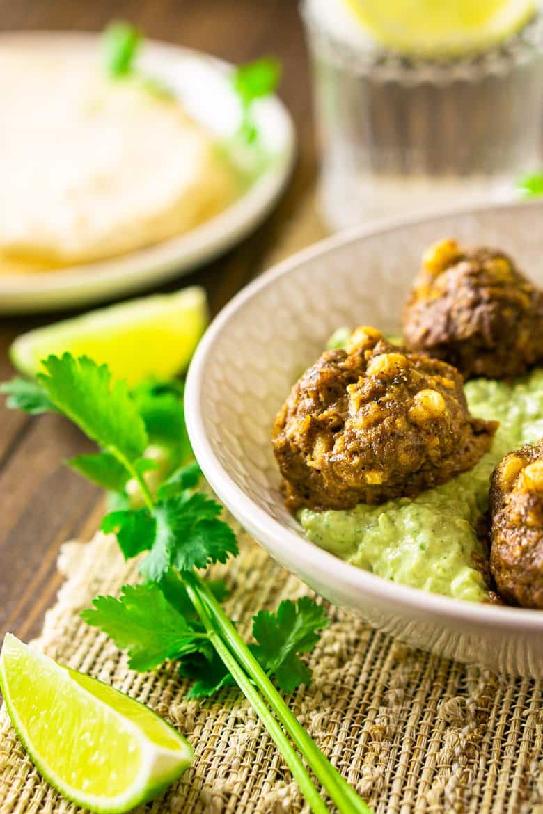 The Mexican meatballs in a shallow bowl with a stack of tortillas in the background.