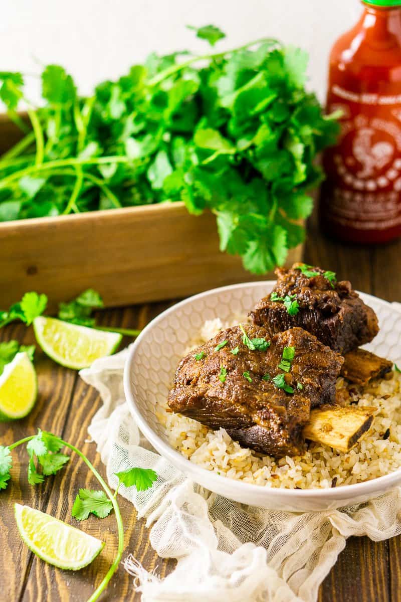 Looking down from an aerial view of two Asian-inspired short ribs with a bottle of sriracha.