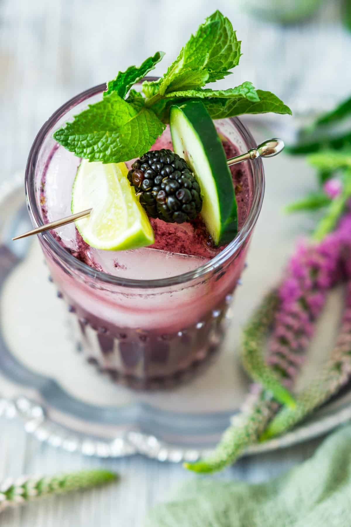An aerial view of the blackberry cucumber spritzer on a silver platter.