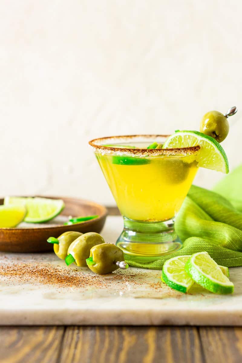 Looking straight on to a Mexican martini on a wood surface and marble platter.