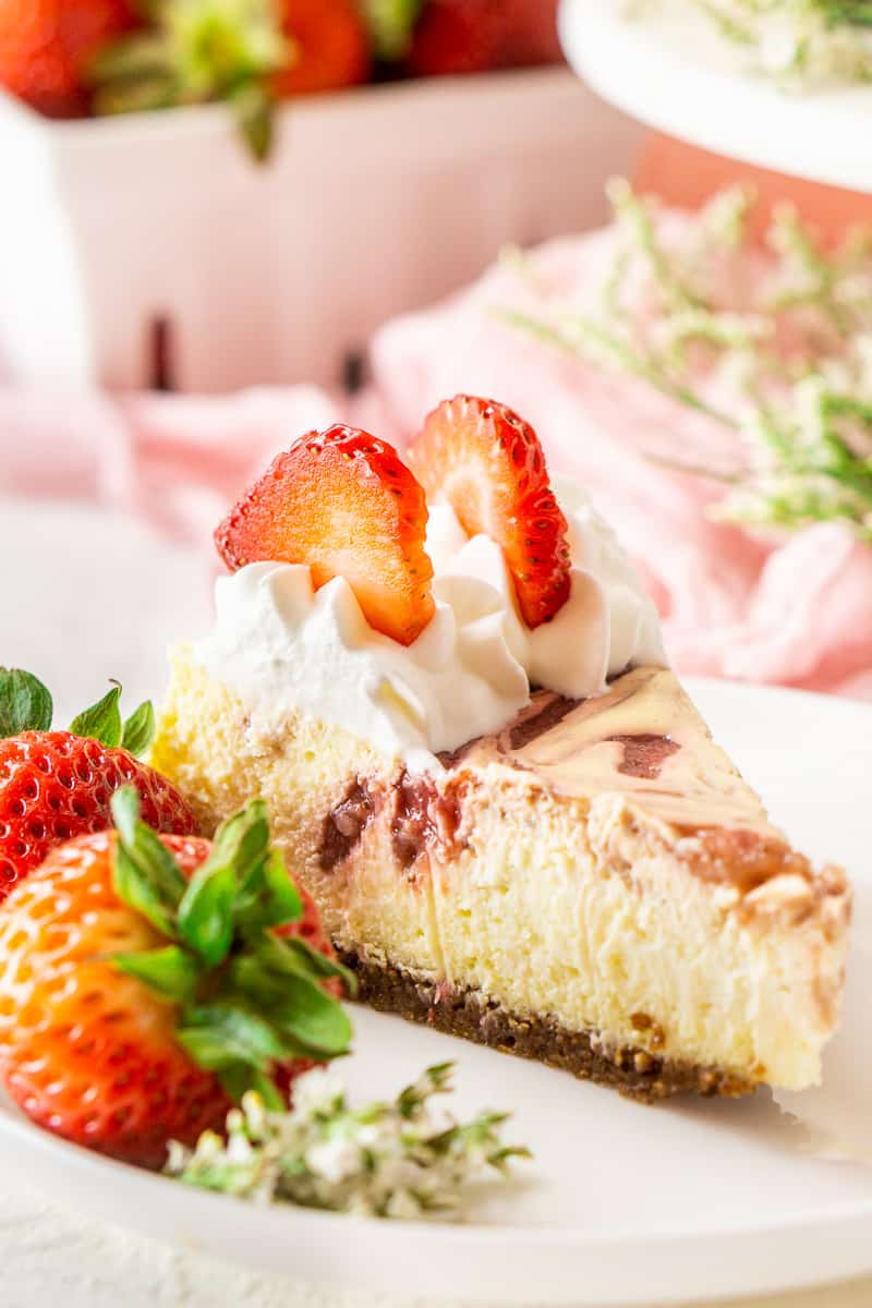 A close-up shot of a slice of fresh strawberry-ginger cheesecake on a white plate.