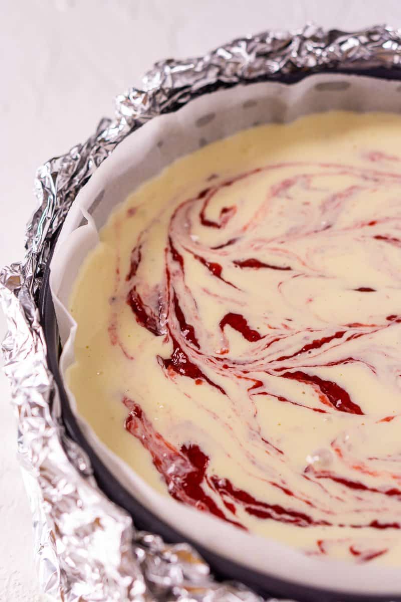 The strawberry-ginger sauce swirled into the cheesecake batter in a springform pan.