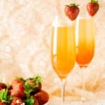 Two honeyed strawberry-rhubarb mimosas with a plate of strawberries on the side.