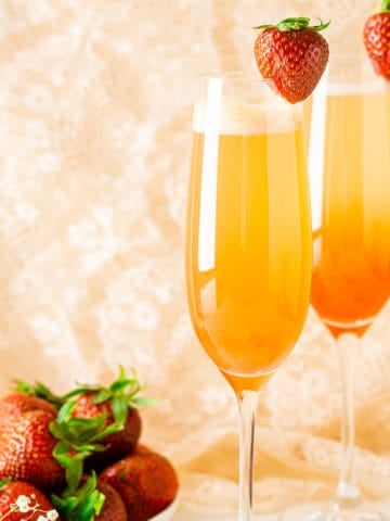 Two honeyed strawberry-rhubarb mimosas with a plate of strawberries on the side.
