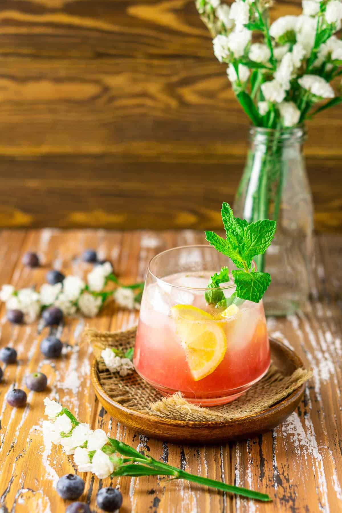 Looking down at a blueberry bourbon smash on a wooden background.