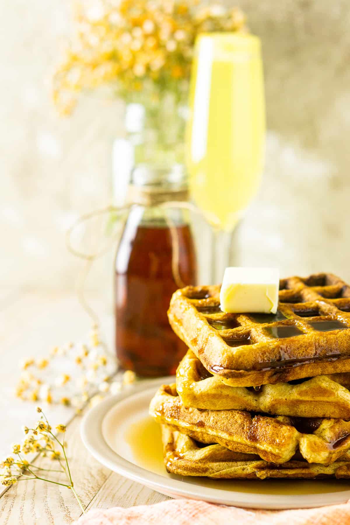 A side view of the buttermilk waffles with flowers and a mimosa.