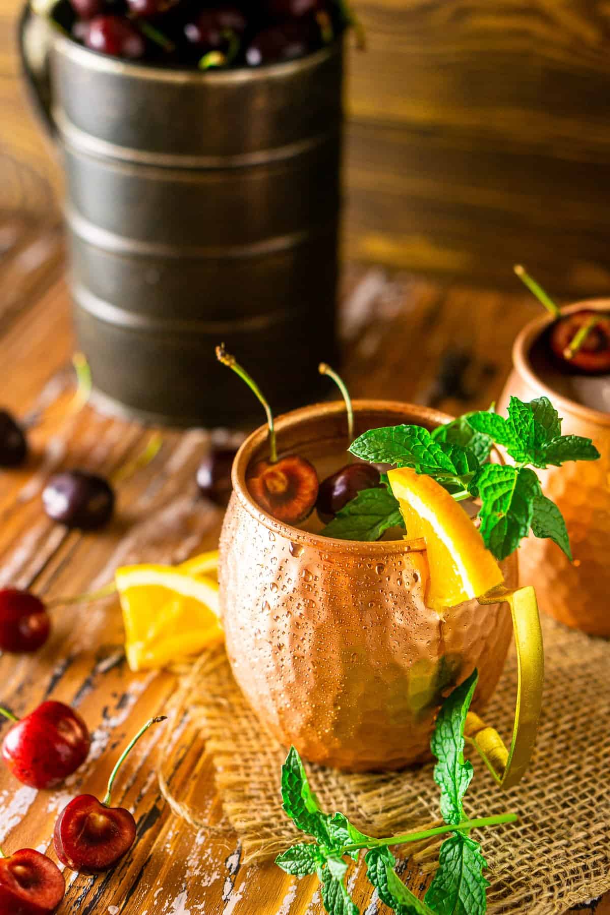 A cherry-orange Kentucky mule with a sprig of mint on burlap.