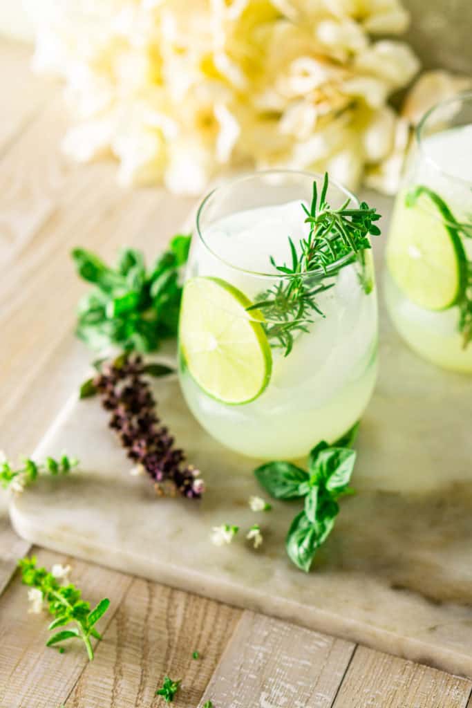 An aerial view of two garden gin and tonics with white flowers tucked in the corner.