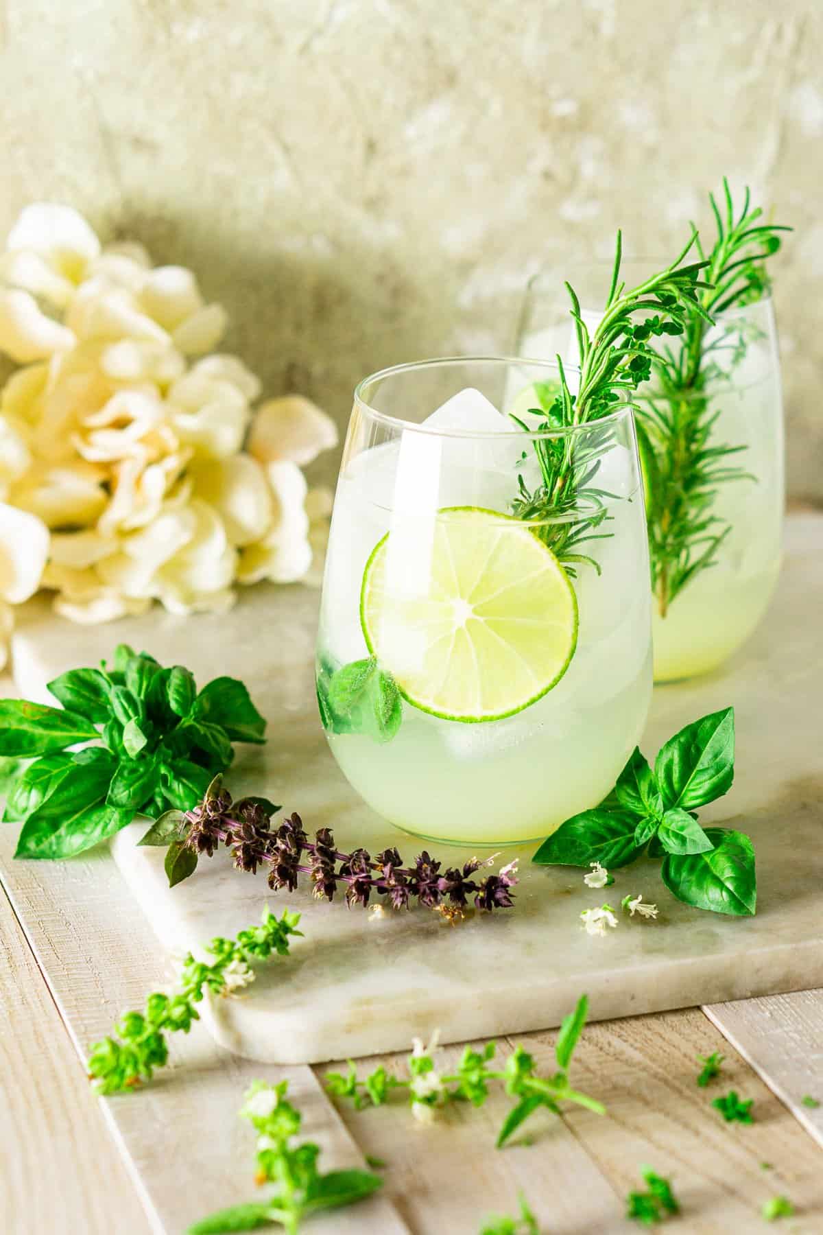 A garden gin and tonic from the side on a marble board with white flowers.