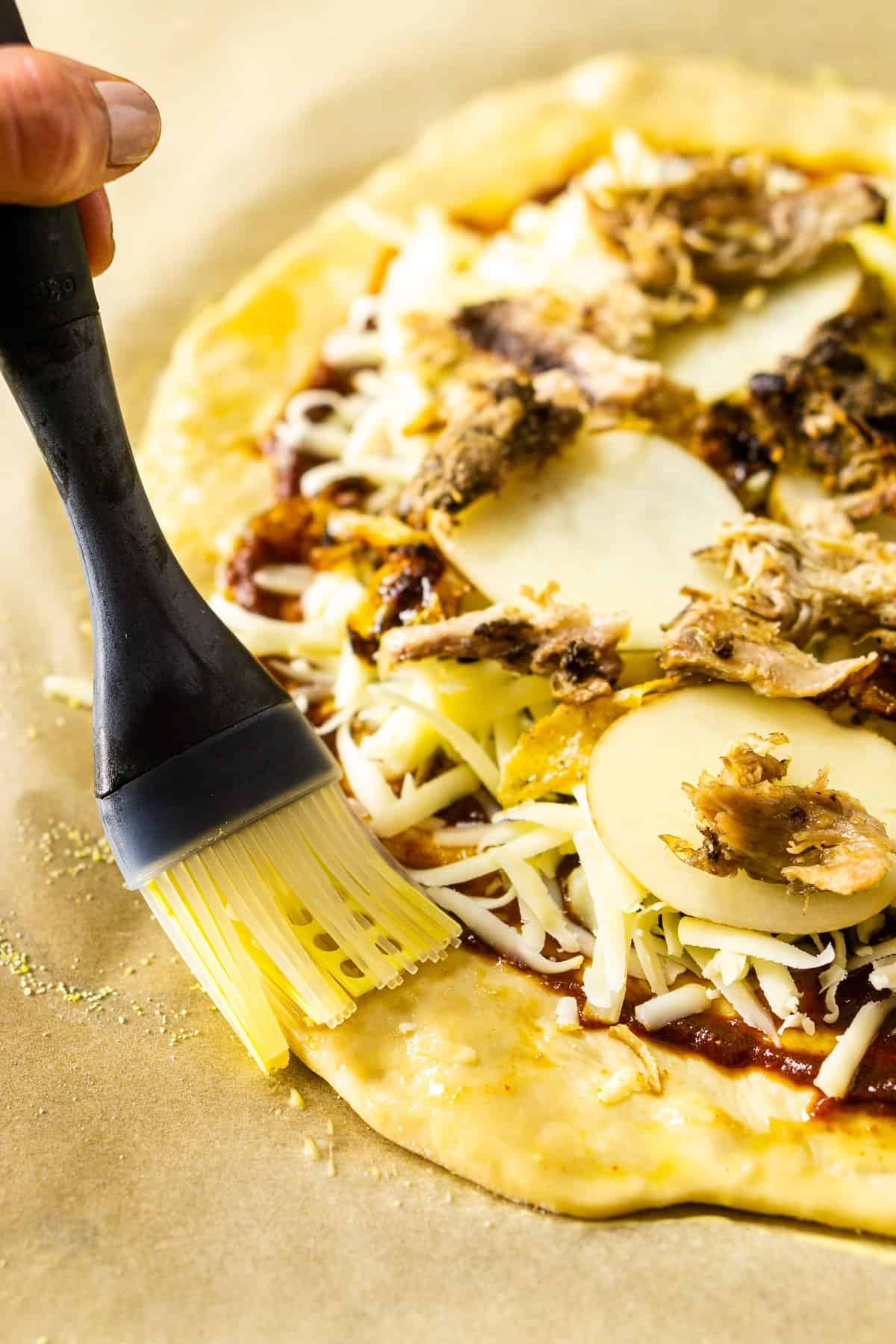 Brushing the off wash onto the pizza dough.