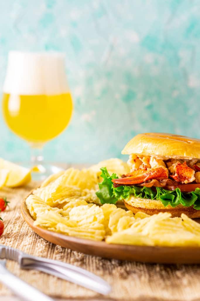 A straight-on shot of the lobster BLT with a beer in the background.