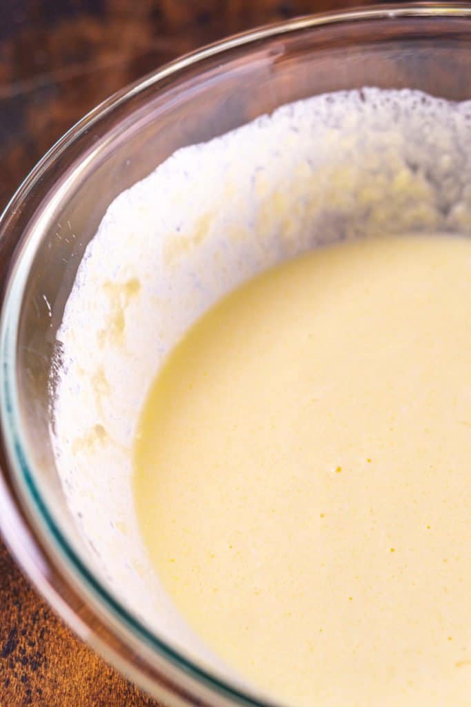 The wet ingredients in a large mixing bowl after they're been combined to create a smooth mixture.