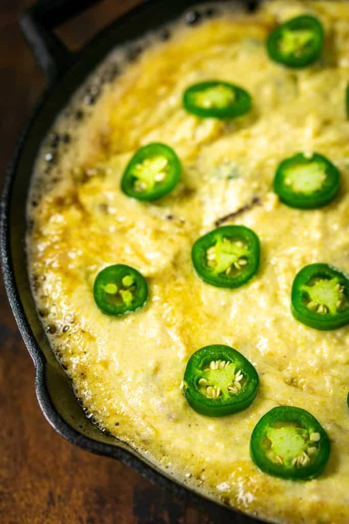 The jalapeno slices on top of the cornbread batter in the cast-iron skillet before baking.