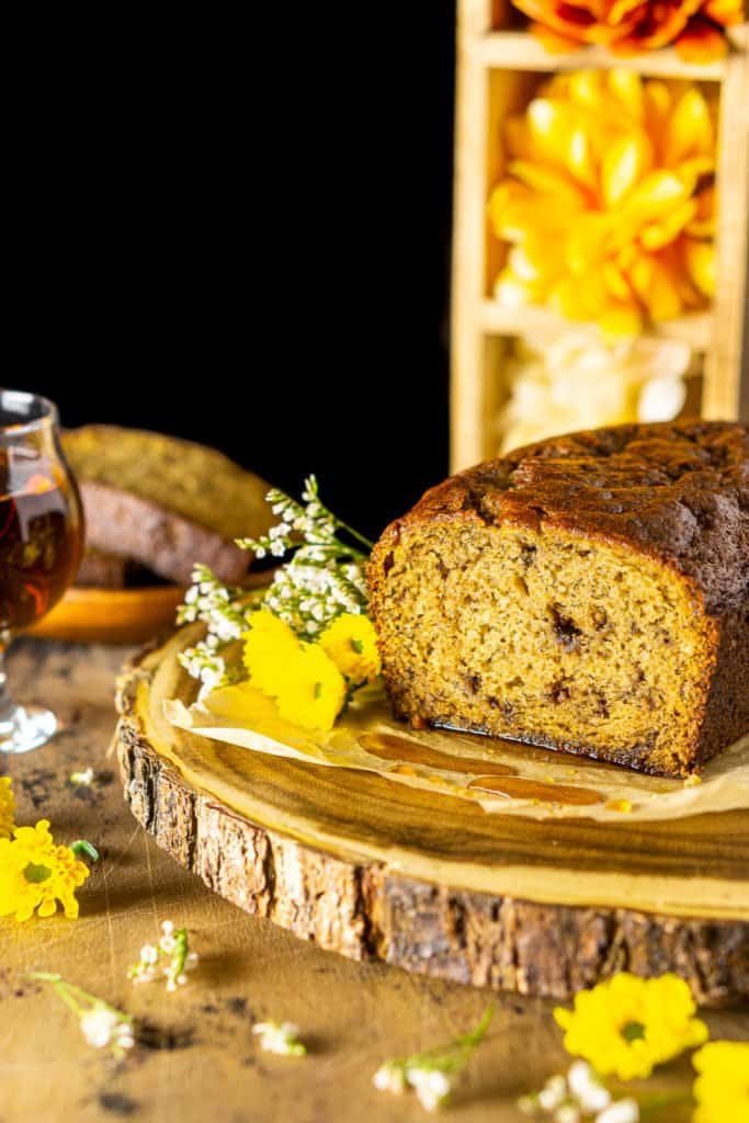 The maple-bourbon banana bread with a stack of flowers in the background.