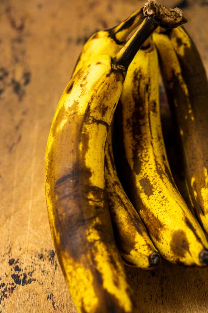 Bananas that have been ripened and show off large brown spots all over the fruit.