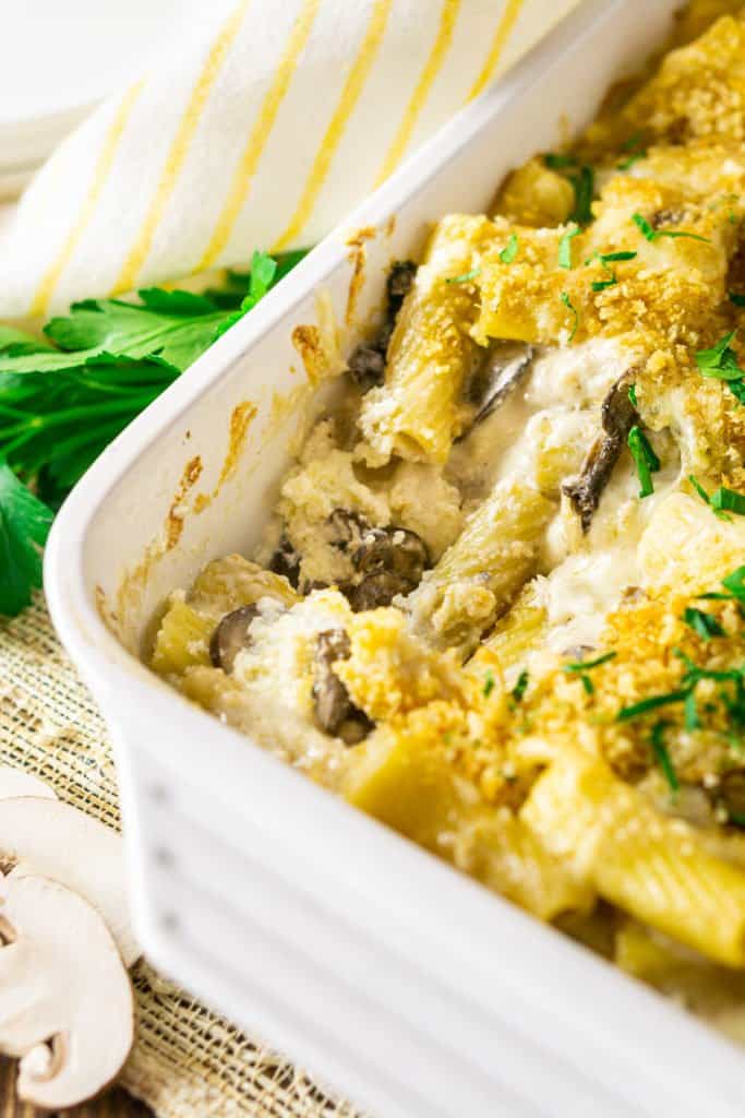 The truffled mushroom white baked ziti in a casserole dish after it's been scooped showing off the creamy center.
