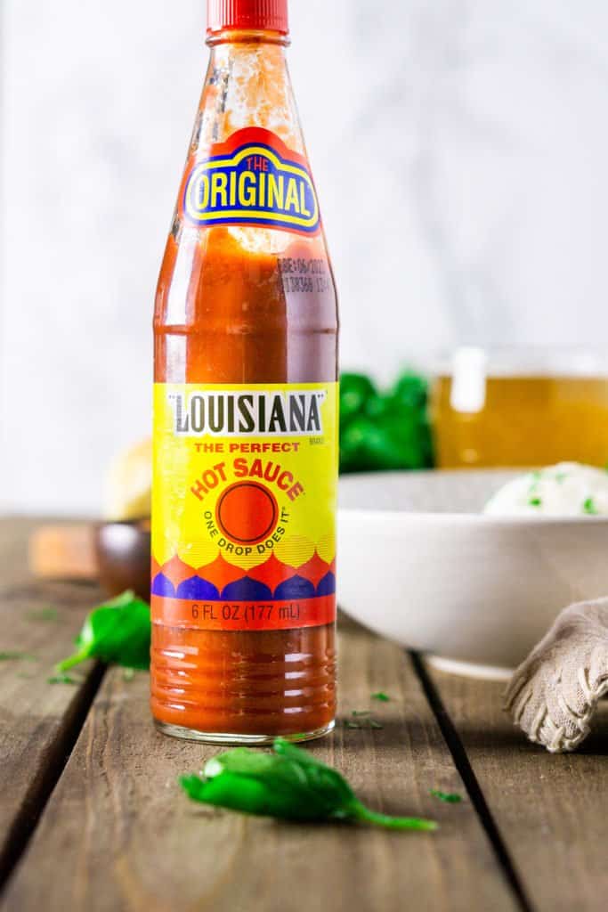 A bottle of Louisiana Hot Sauce with a bowl of gumbo in the background.