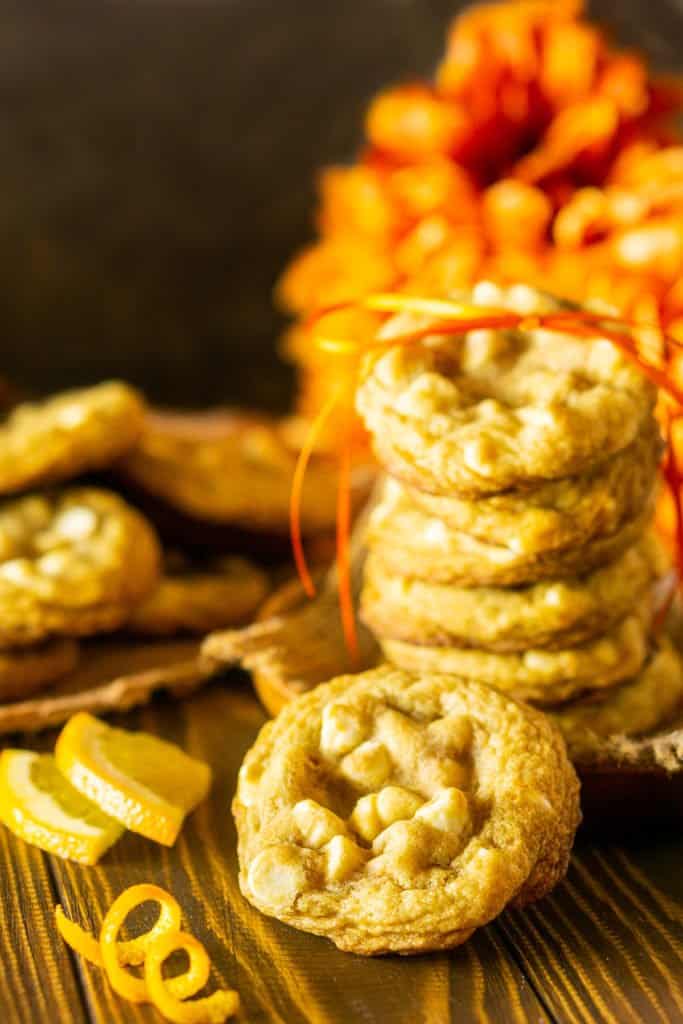 A close-up of a single maple-ginger cookie with a stack of cookies behind it.