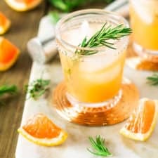 A rosemary-grapefruit spritzer from the front and top on a marble tray.