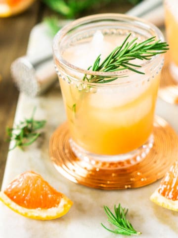A rosemary-grapefruit spritzer from the front and top on a marble tray.
