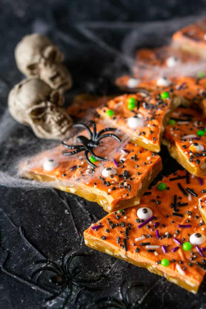 A pile of Halloween toffee with plastic spiders on the side.