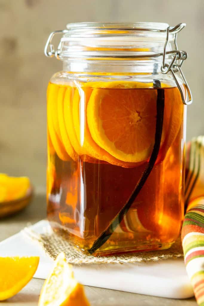 A close-up shot of the vanilla bean and orange infused bourbon on a serving tray with a fall-colored napkin to the side.