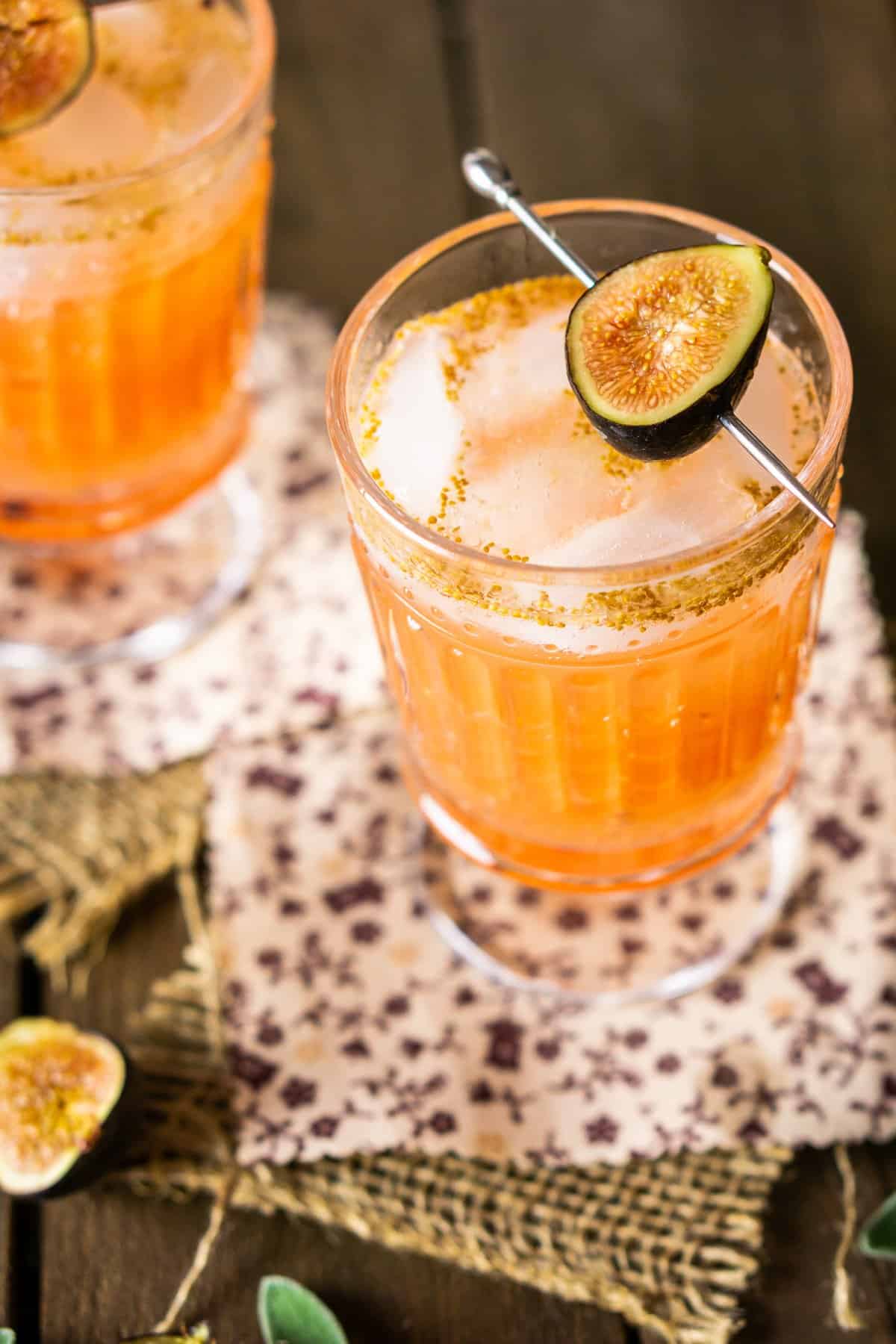 A close-up of a sage-fig cocktail with a fig next to it.