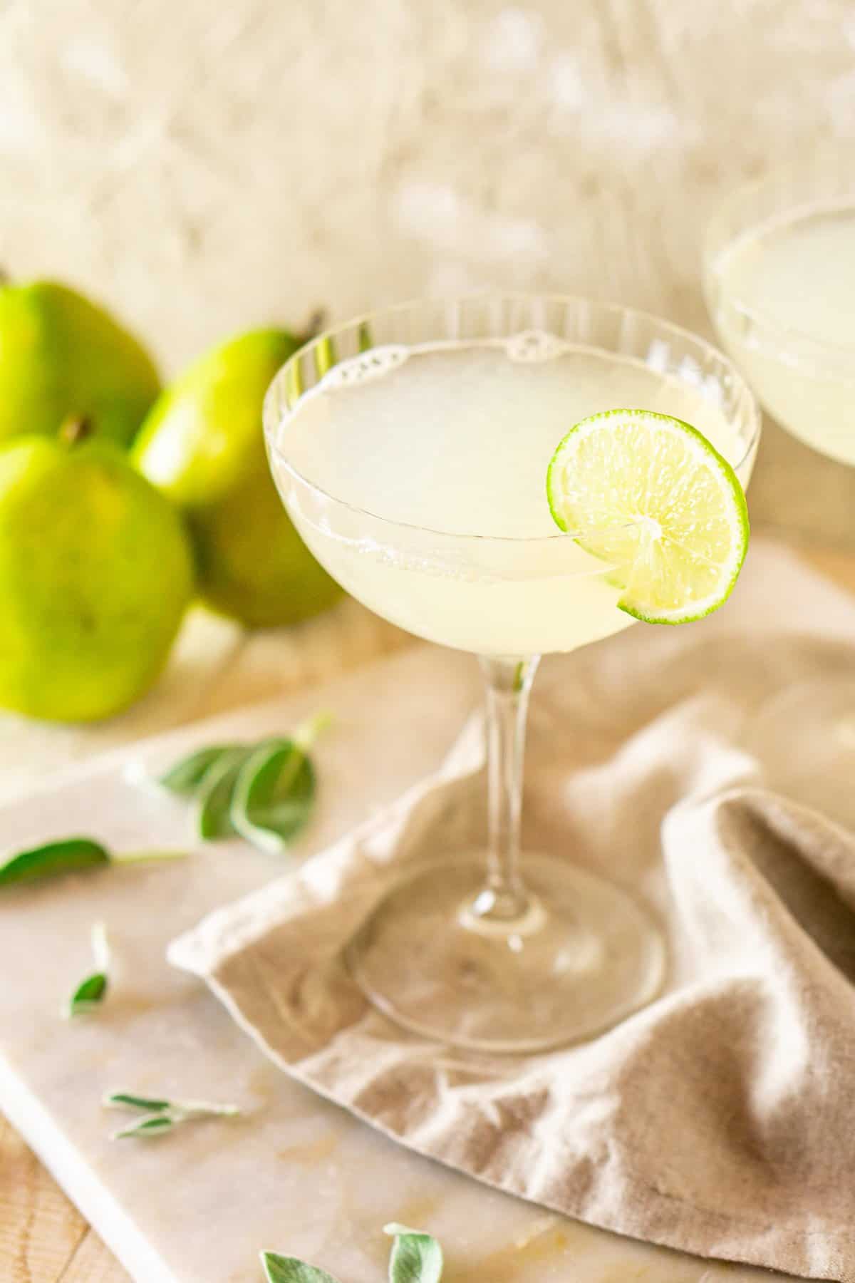 One pear-sage gimlet on a neutral-colored napkin and white marble board.