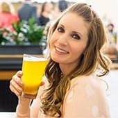 A headshot of Amanda, the owner of Burrata and Bubbles, holding a beer.