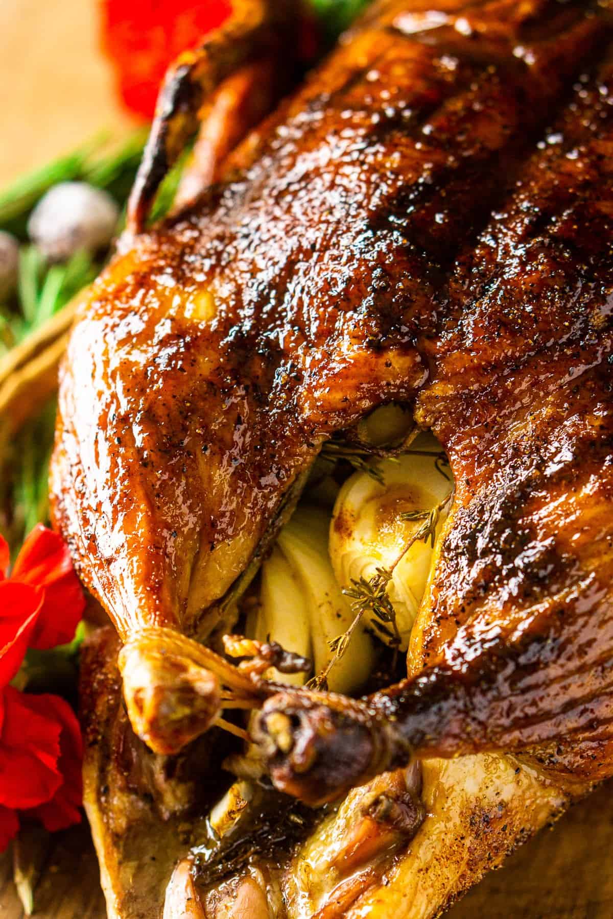 Looking down on the roasted duck from the side with rosemary sprigs in the background.